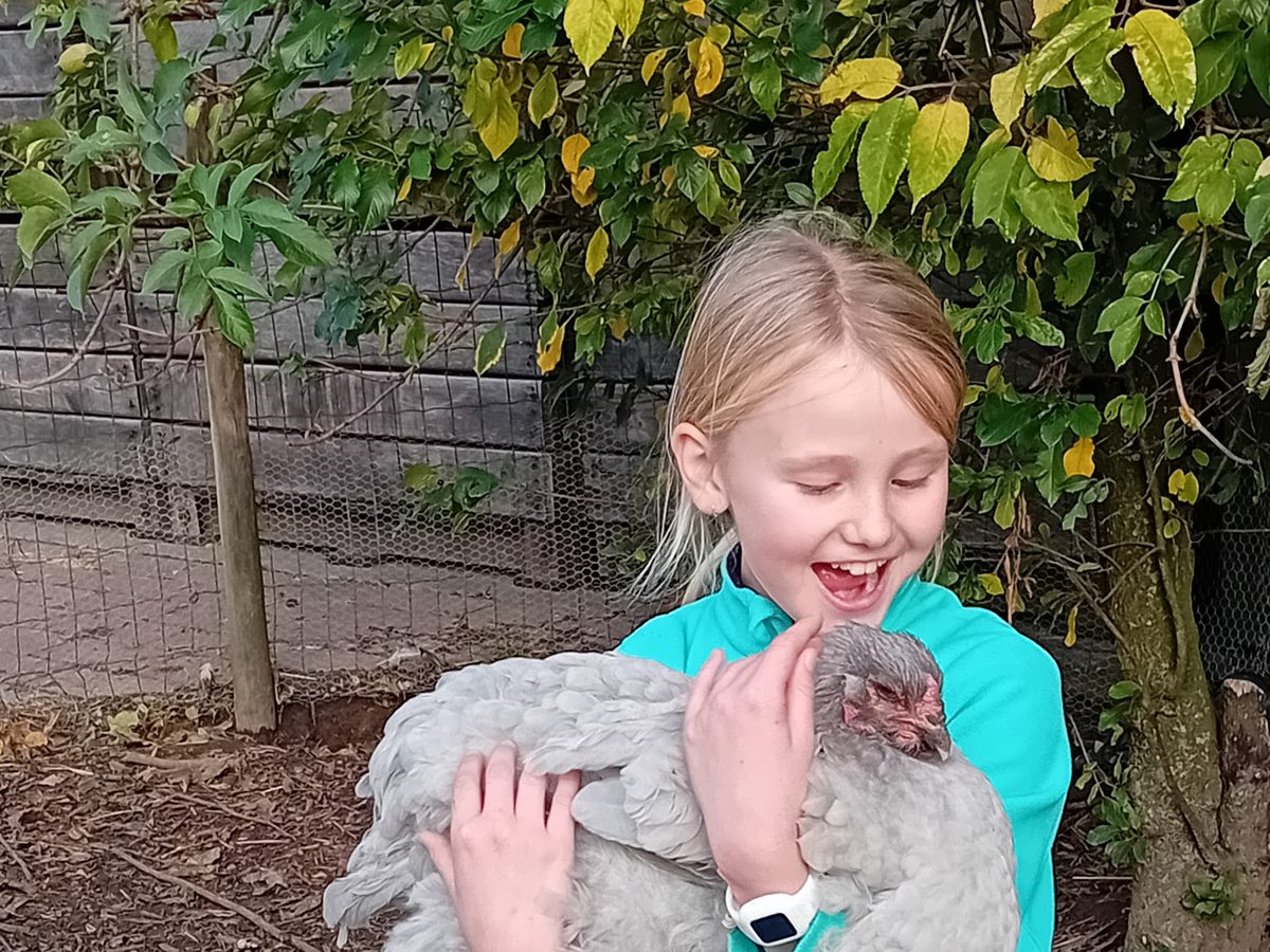 Kampkind knuffelt lachend een hen